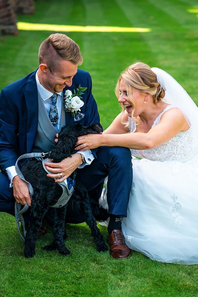 A bride and groom hugging their dog on their wedding day the Royal Berkshire Hotel
