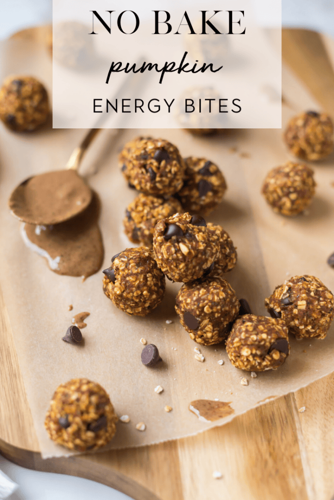 No bake pumpkin energy bites on wax paper on top of cutting board with spoon of almond butter