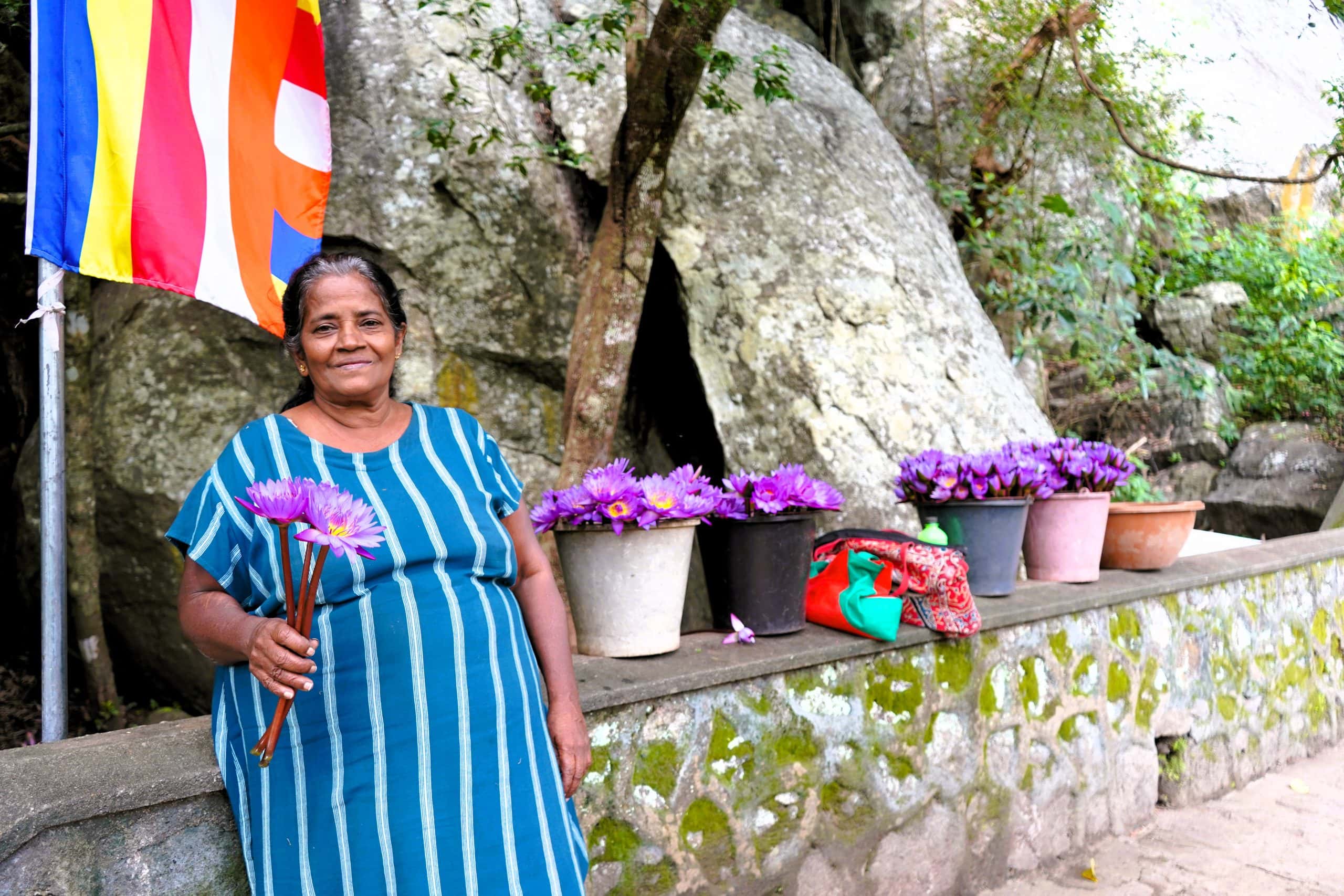 woman giving out flowers at dambulla cave temple