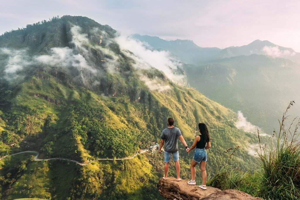 The couple greets the sunrise in the mountains. Man and woman in the mountains. Man and woman holding hands. The couple travels around Asia. Travel to Sri Lanka. Serpentine in the mountains. Honeymoon
