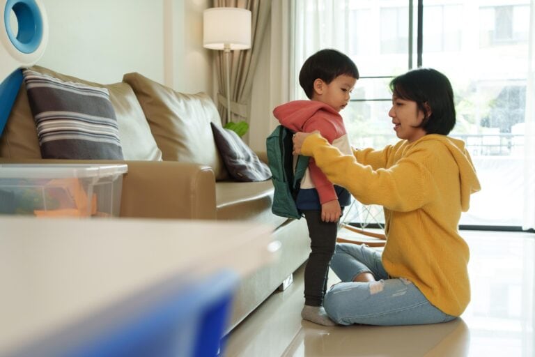 mom putting on her kid's backpack
