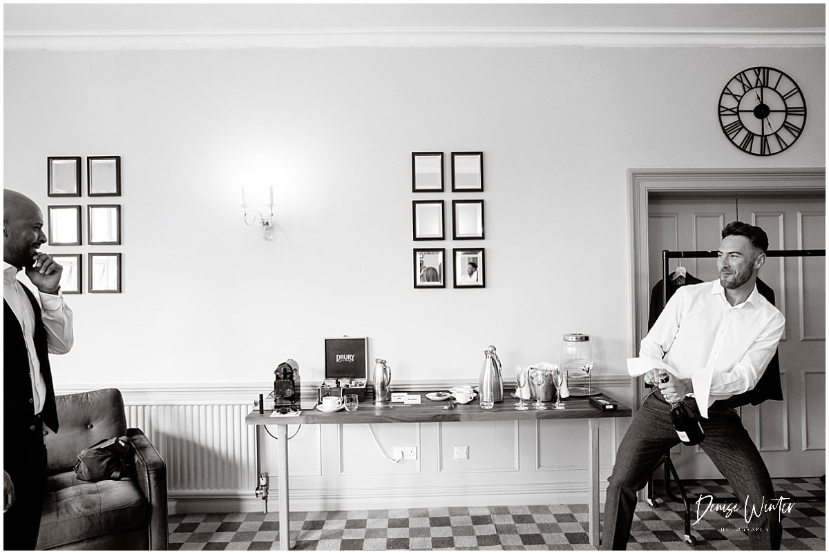 Groom popping champagne bottle