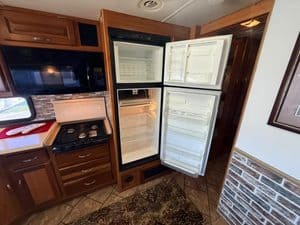 Open RV refrigerator showing empty shelves and freezer compartment.
