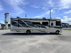 Modern Coachmen Mirada 35OS RV parked outdoors under blue sky.