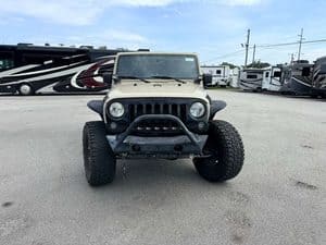 Jeep vehicle in RV dealership lot with RVs in background.