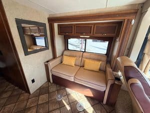 Cozy RV living space with sofa, window, and wooden cabinets.