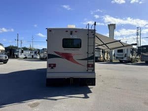 Rear view of a travel trailer with an awning at RV repair shop.
