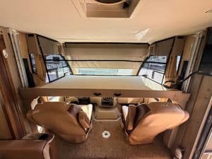 Interior view of a recreational vehicle with bed and seating area.