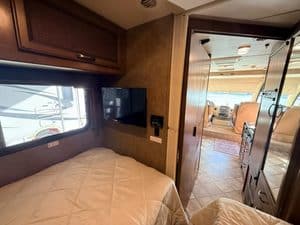 Cozy RV bedroom with TV and view into the living area.