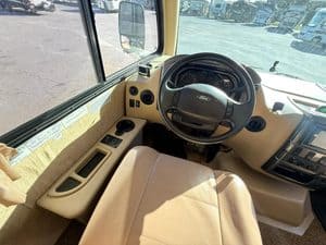 Interior view of an RV driver's cabin with steering wheel and dashboard.