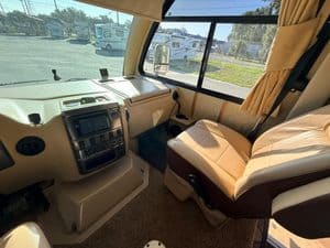 Interior view of RV dashboard and passenger seat with large front window.