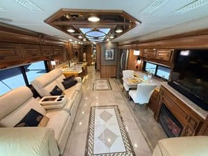Luxury RV interior with leather sofas, dining area, and entertainment center.
