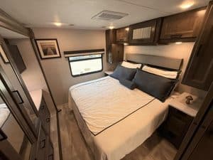 Comfortable RV bedroom with large bed and storage cabinets in Coachmen Mirada 35OS.