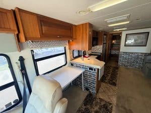 RV interior with kitchen, seating, and large window for scenic views.