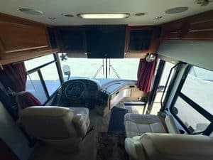 Interior view of a luxury RV with comfortable seats and large front windshield.