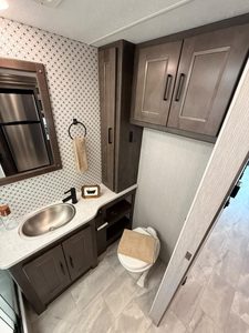 Small RV bathroom with sink, cabinets, and toilet in a Coachmen Mirada 35OS.