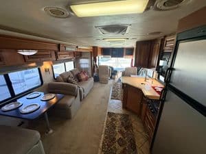 Spacious RV interior with sofa, dining area, and kitchen cabinets.