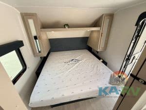 Interior view of 2026 Acclaim 2500RD RV with bed and storage cabinets.