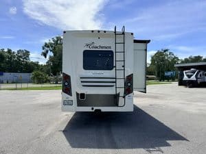 Rear view of Coachmen Mirada 35OS RV with ladder and slide-out.