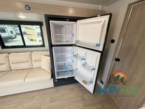 RV refrigerator open showing interior storage and shelves.