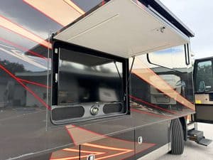 RV kitchen with open slide-out and entertainment center for luxury travel.