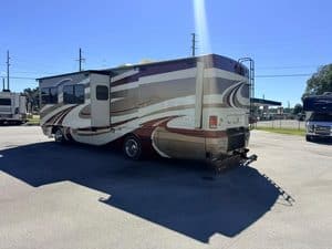 Large beige and brown RV parked outdoors on a sunny day.