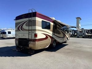 Luxury RV with beige and maroon exterior parked at dealership lot.