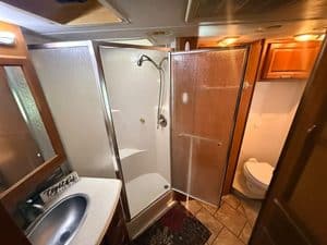 RV bathroom with shower, toilet, and sink for travel comfort.