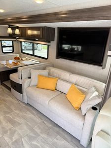 Comfortable RV living space with sofa, TV, and dining area in 2023 Coachmen Mirada 35OS.