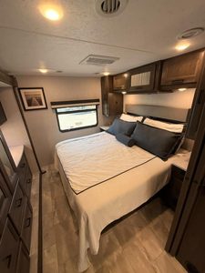 Cozy RV bedroom with bed, pillows, and storage cabinets in a Coachmen Mirada 35OS.