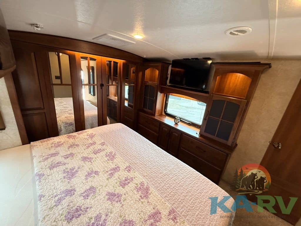 RV bedroom interior with wooden cabinets and window for optimal comfort.