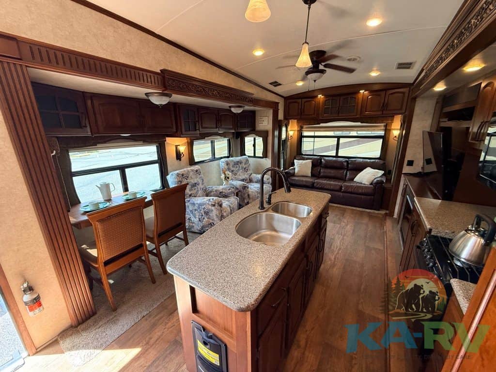 RV interior with kitchen and seating area, modern design, and large windows.