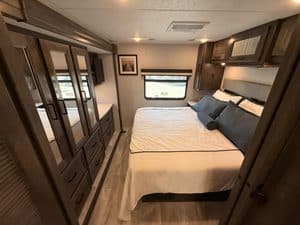 RV bedroom interior with storage cabinets and large window.