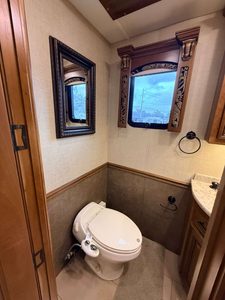 Elegant RV bathroom with window, mirror, and wooden accents.