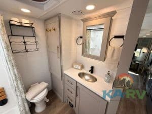 Modern RV bathroom with sink, mirror, and storage cabinets.