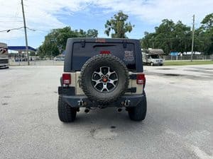 Rear view of a 2016 Entegra Cornerstone 45B RV with spare tire and parking lot background.