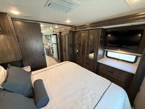 RV bedroom interior with TV and storage cabinets in 2023 Coachmen Mirada 35OS.