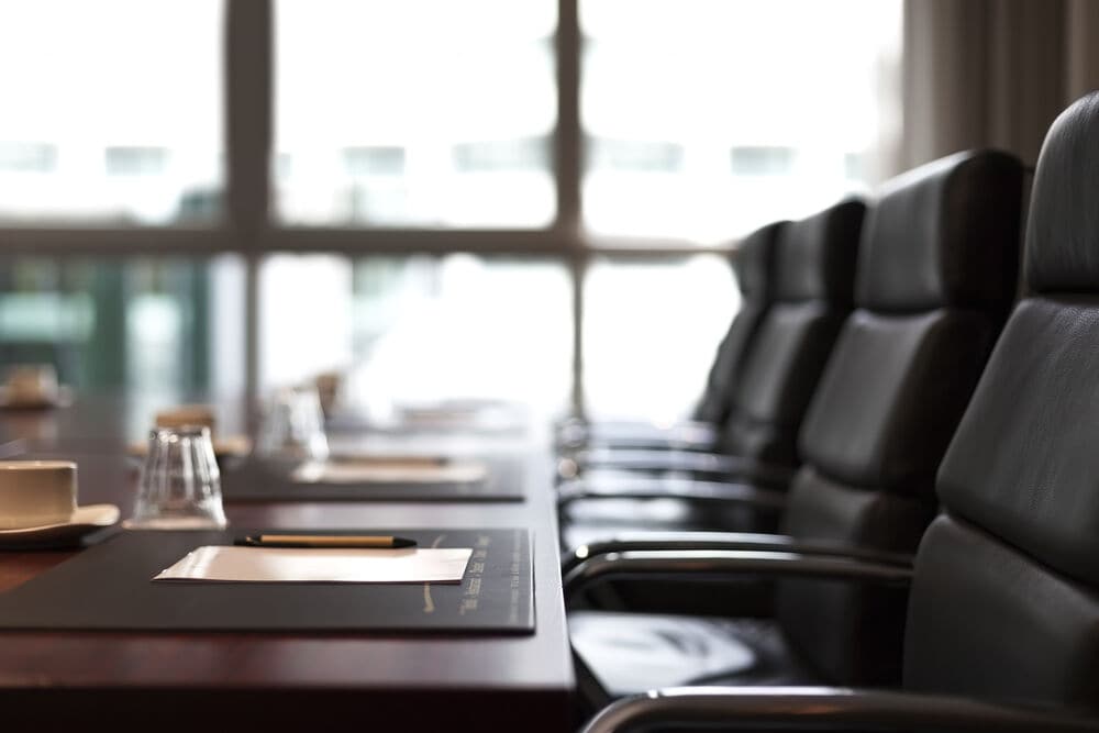 Empty board meeting room with table and black chairs