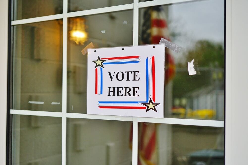 Vote here sign on glass window