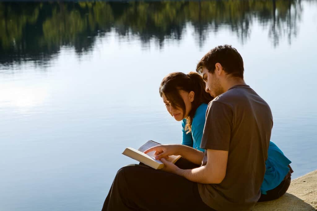 Couple reading in front of water