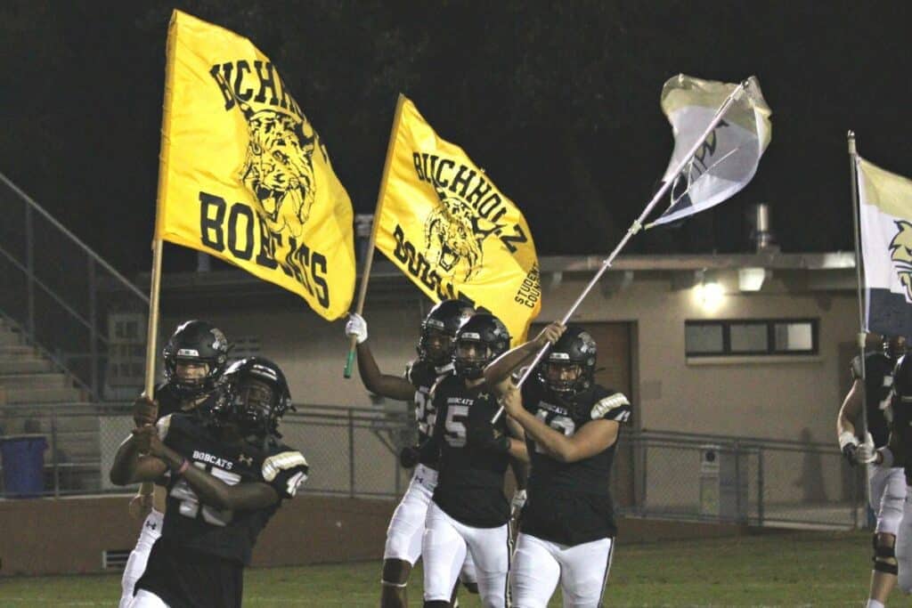 Buchholz football players wave flags during introductions