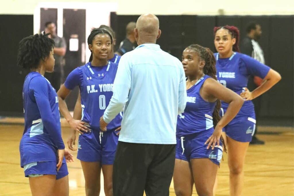 P.K. Yonge girls basketball team with coach on sideline.