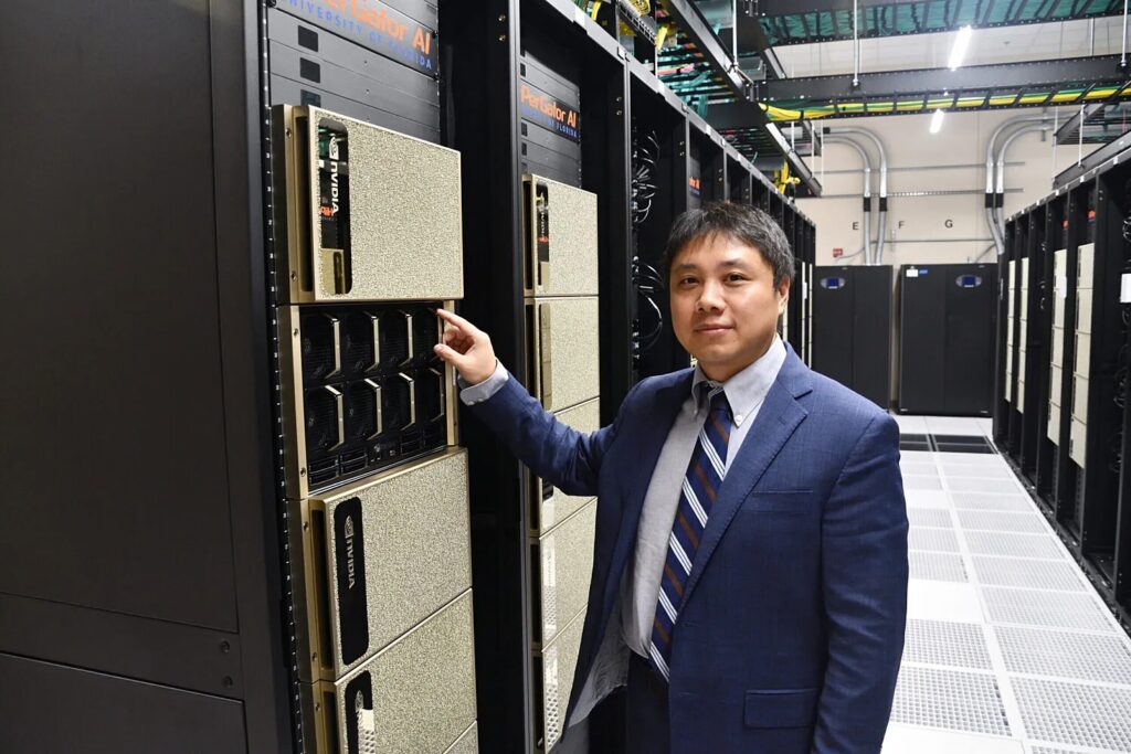 Yonghui Wu, Ph.D., stands beside the HiPerGator, the supercomputer at the University of Florida that supported his research in artificial intelligence, thanks to the processing power of hundreds of synchronized computer units from NVIDIA.