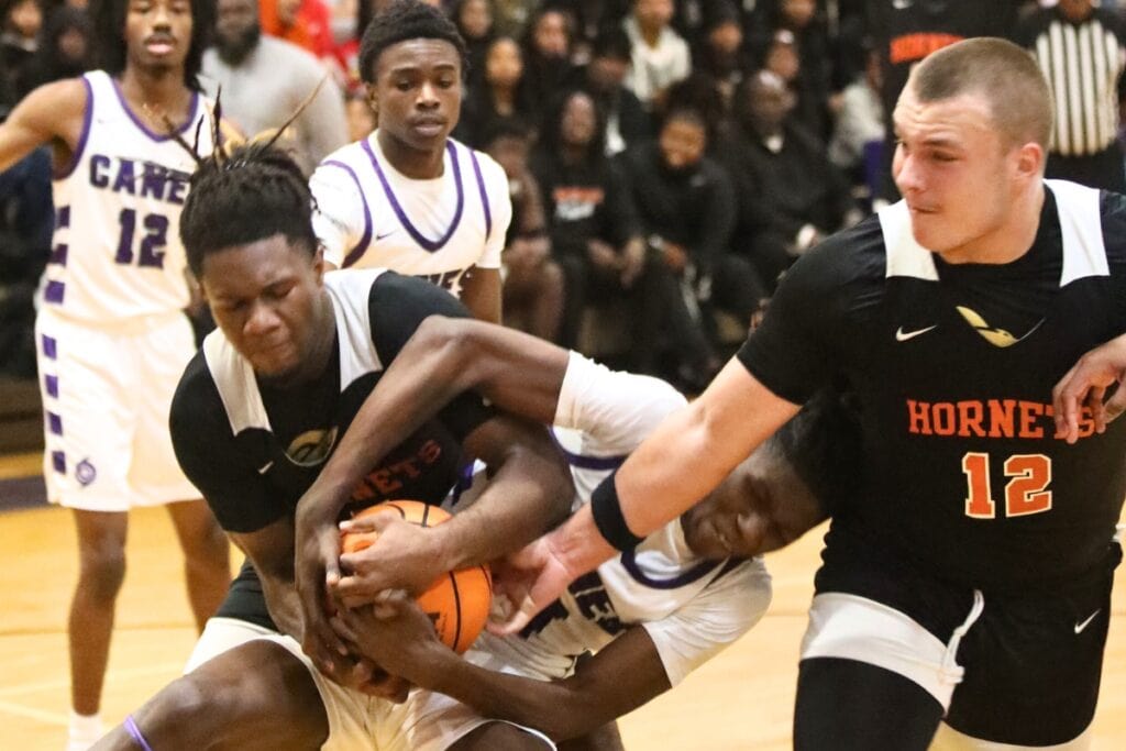 Hawthorne's Caleb Rollerson (5) and Andrew Zock (12) battle Gainesville's Craig Thomas Jr. for the ball.