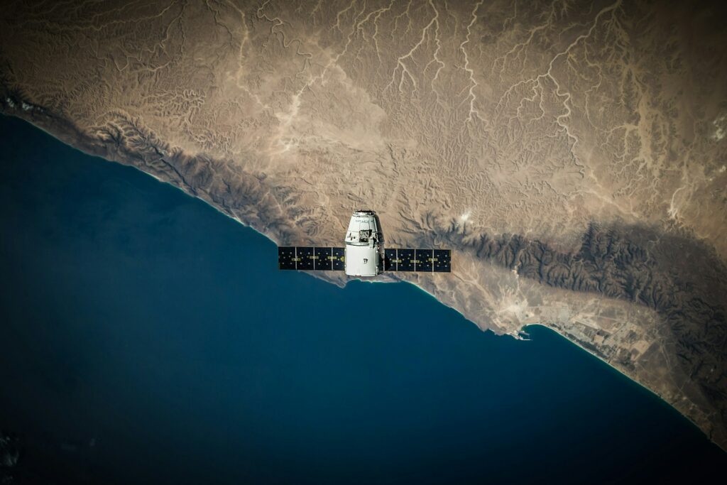 satellite orbits in space with ocean and land below.