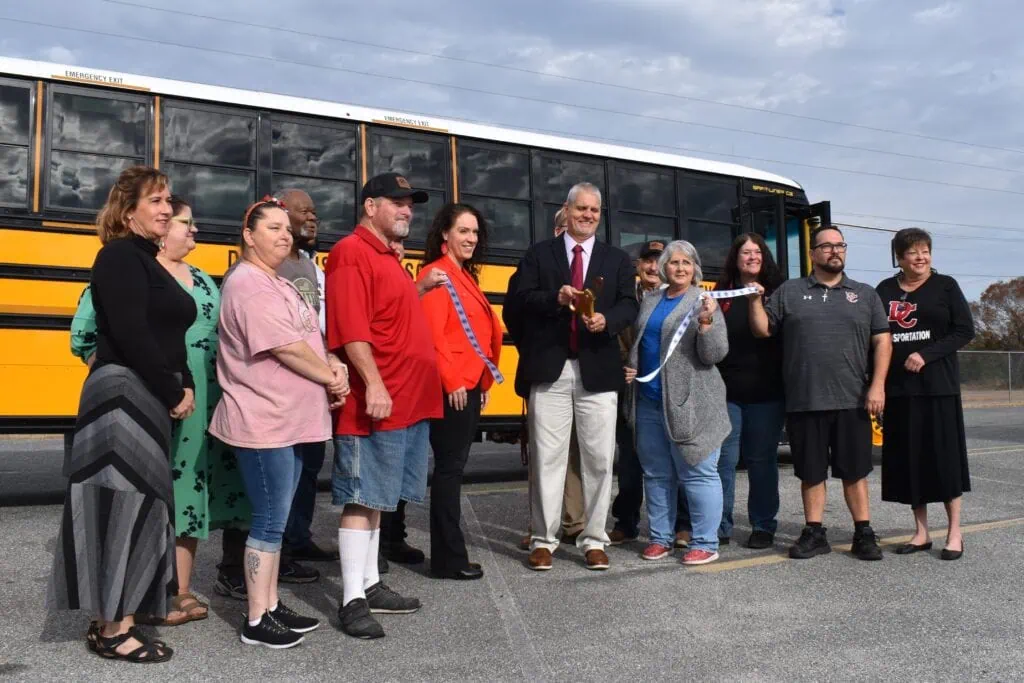 DCPS Superintendent Mike Thomas cuts a ribbon to celebrate the new EV fleet, with the help of the district's bus drivers.