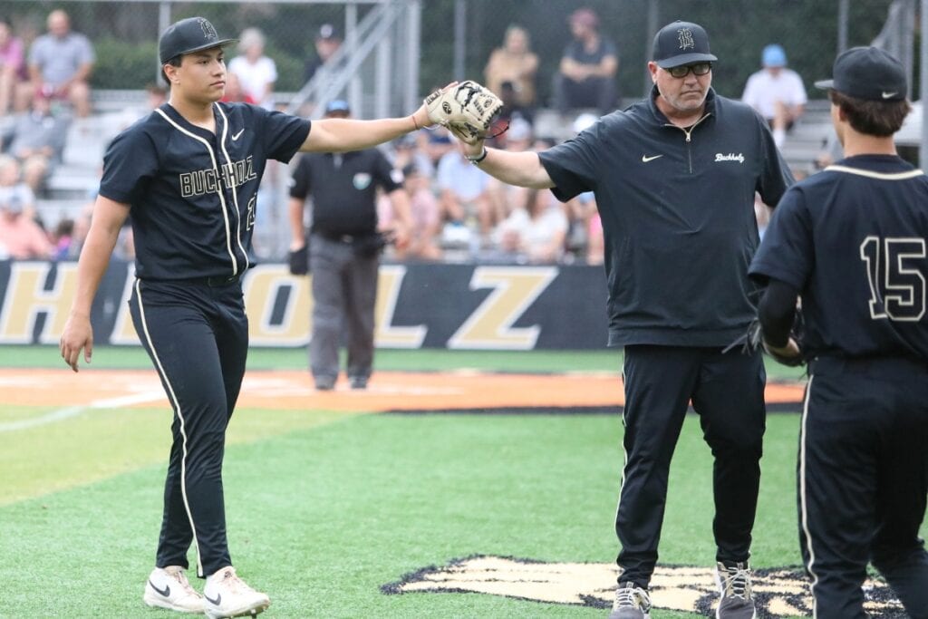 Buchholz's JJ Gardner (21) and coach Ron Brooks high five after a Garnder second-inning strikeout against Tate (Cantonment) in game two of the 6A Regional 1 Semifinals. Photo by C.J. Gish