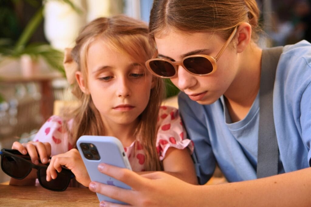 Children looking at cell phone. Photo by Tati Odintsova-unsplash