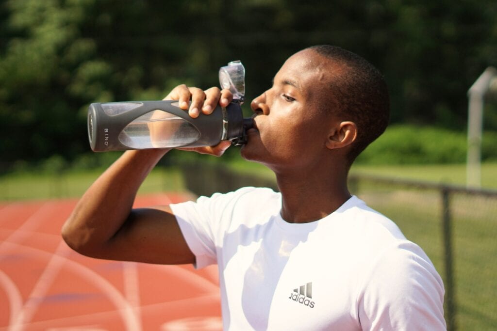 Man drinking water from water bottle. Photo by Nigel Msipa-unsplash