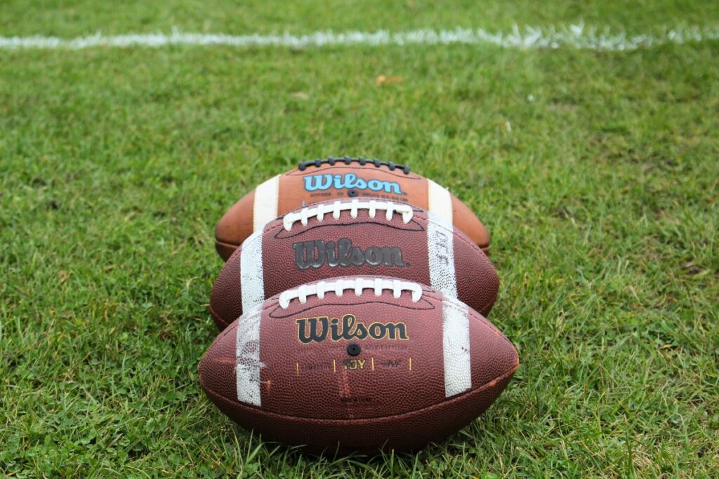 Three footballs. Photo by Melissa McGovern-Unsplash
